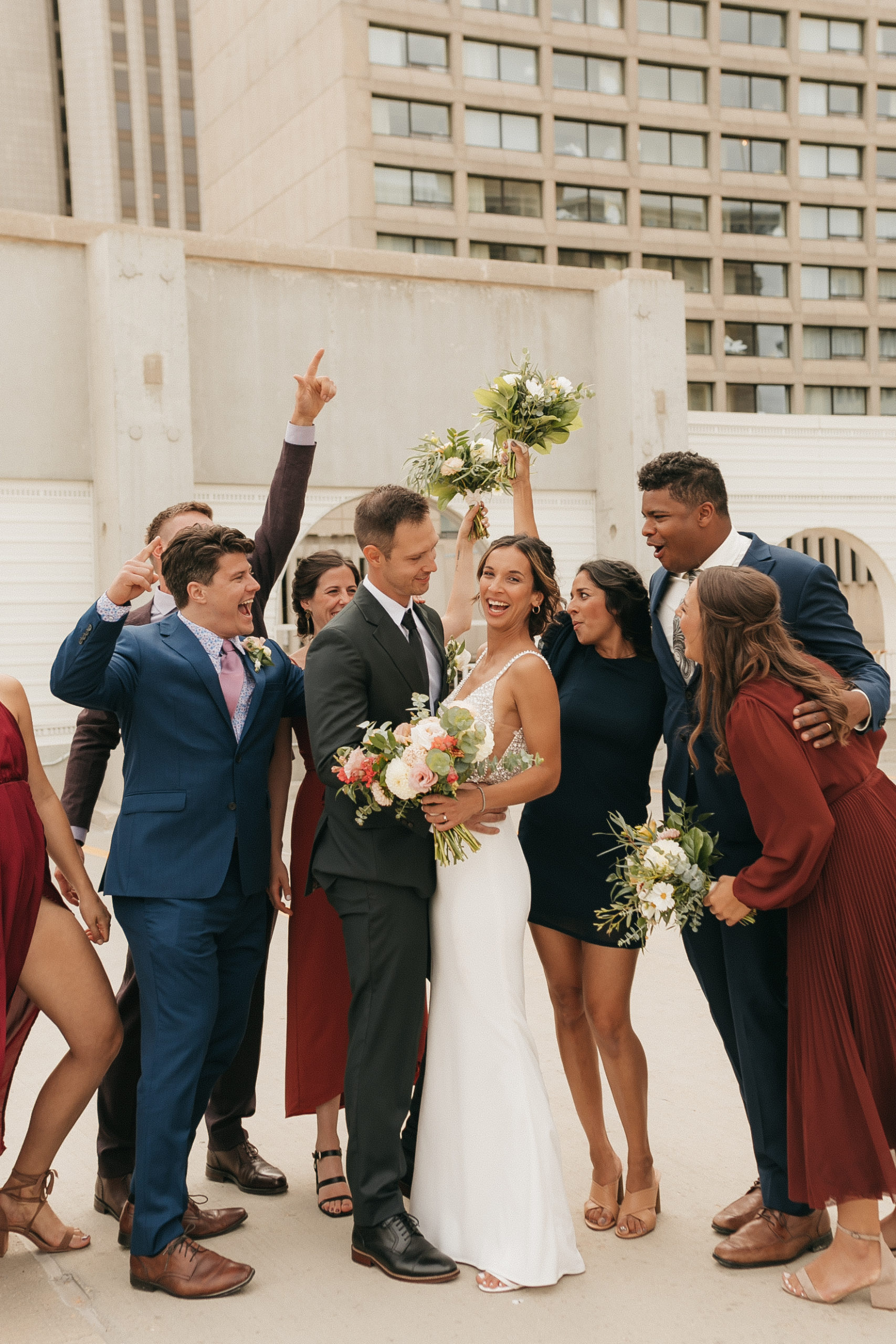 bride and groom surrounded by wedding party laughing