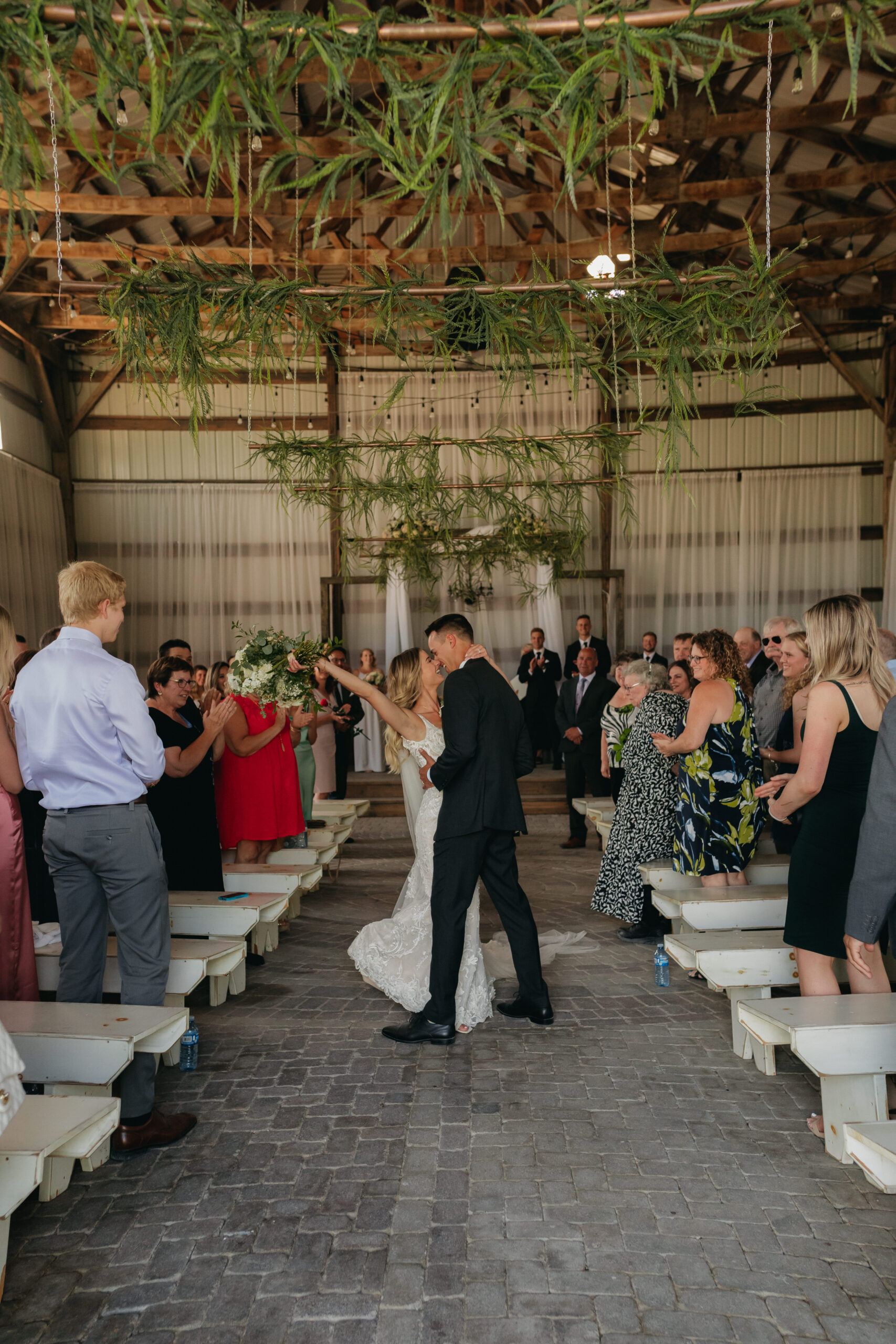 Newlyweds kissing down the aisle and cheering