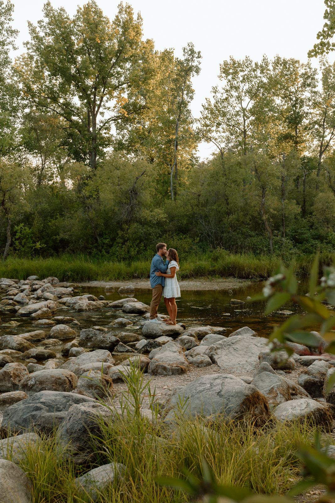 couple kissing on the river rocks