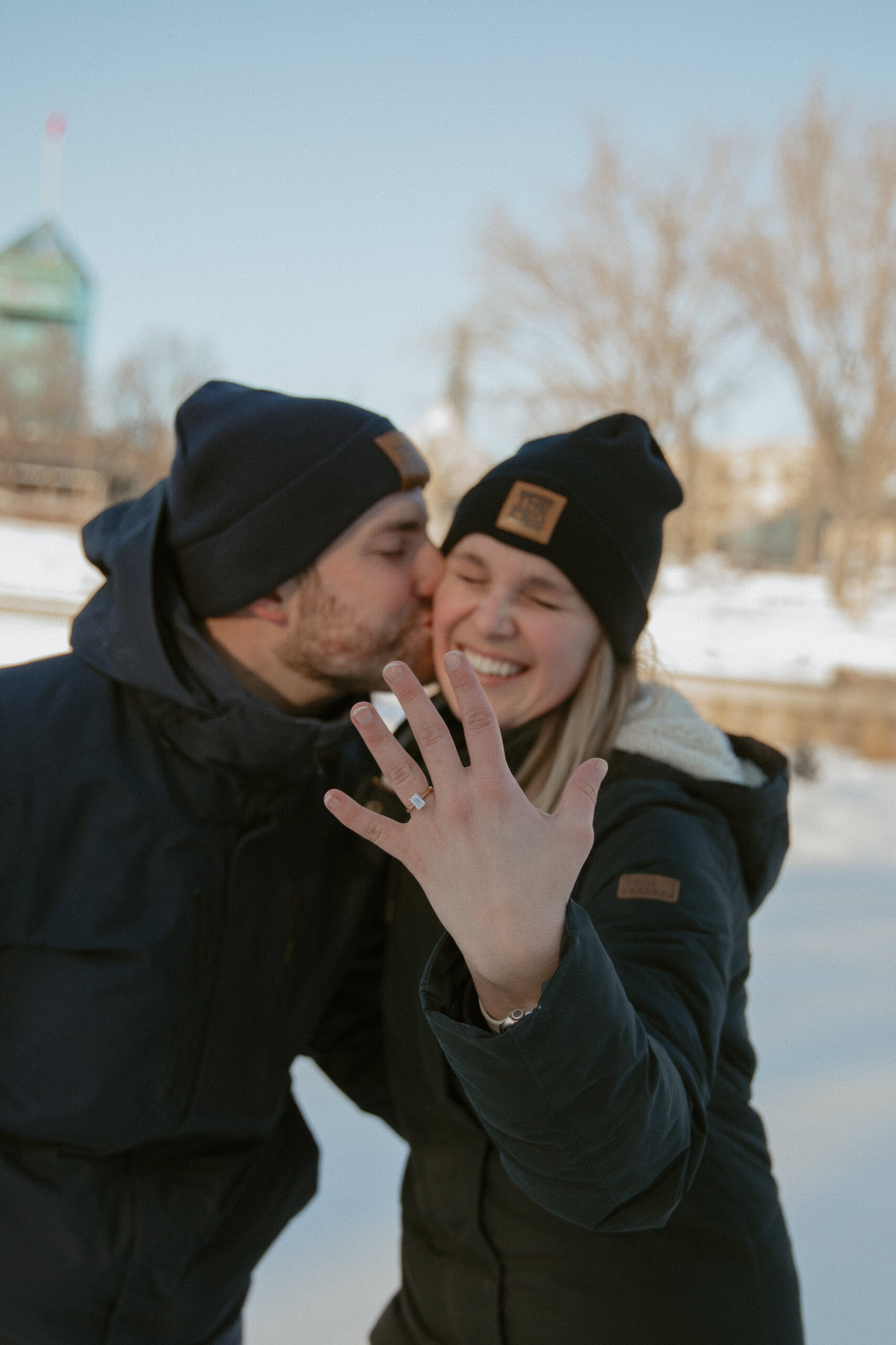 newly engaged couple kissing on a river skating trail