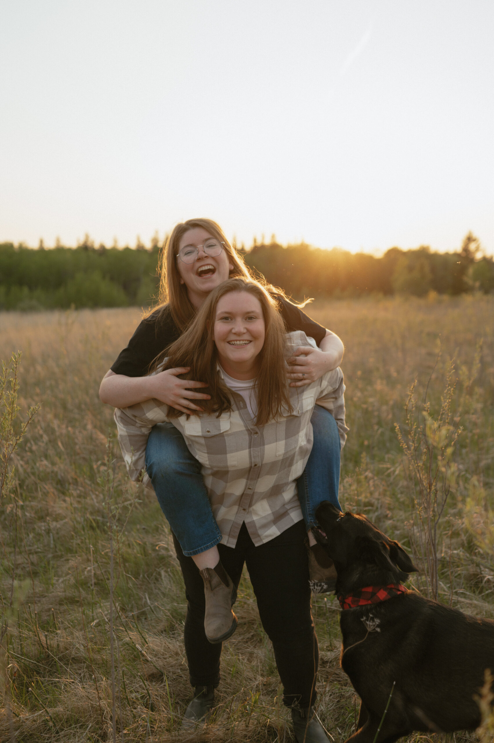 Coupe piggy back riding in a field and laughing