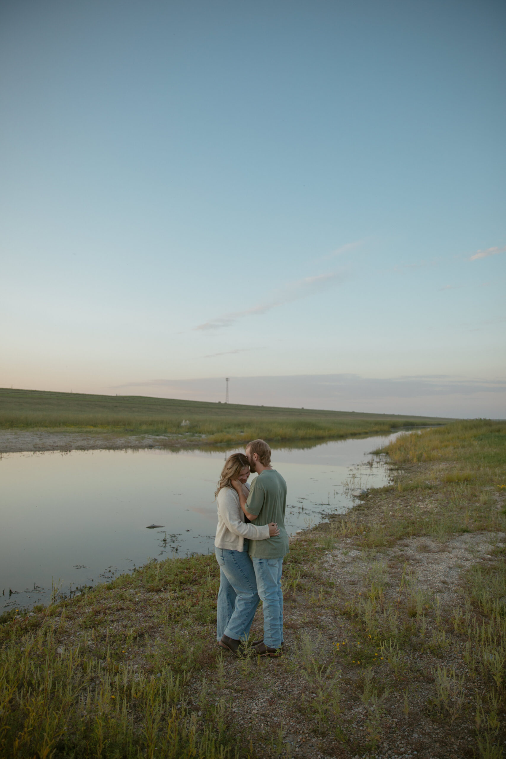 Couple kissing by a pond at cotton candy sunset