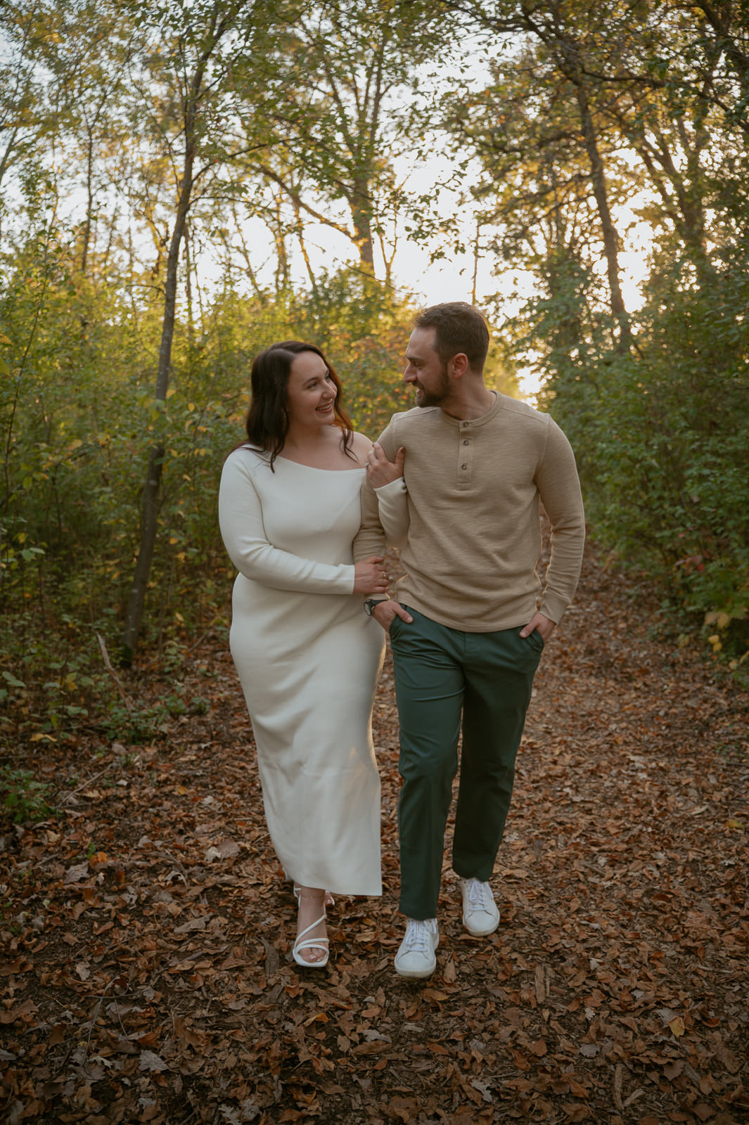 couple walking through fall leaves holding hands