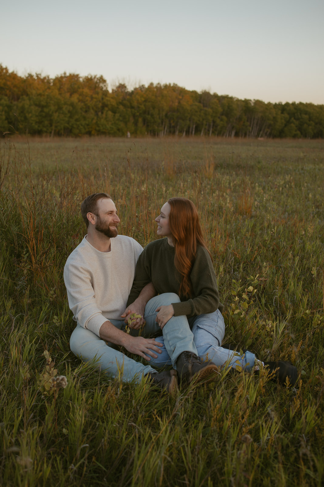 couple sitting in field in autumn golden hour light