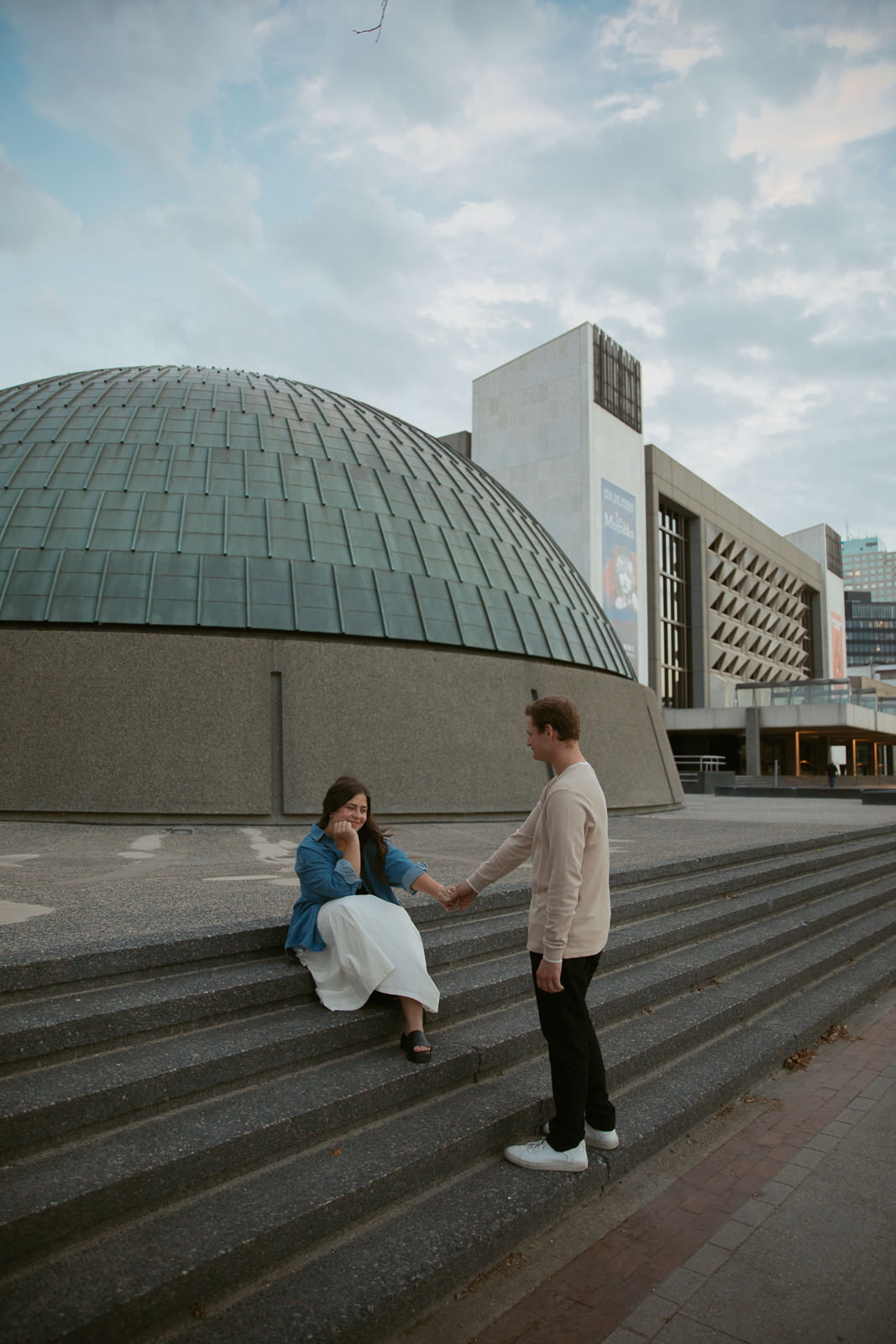 woman sitting on steps holding man's hand