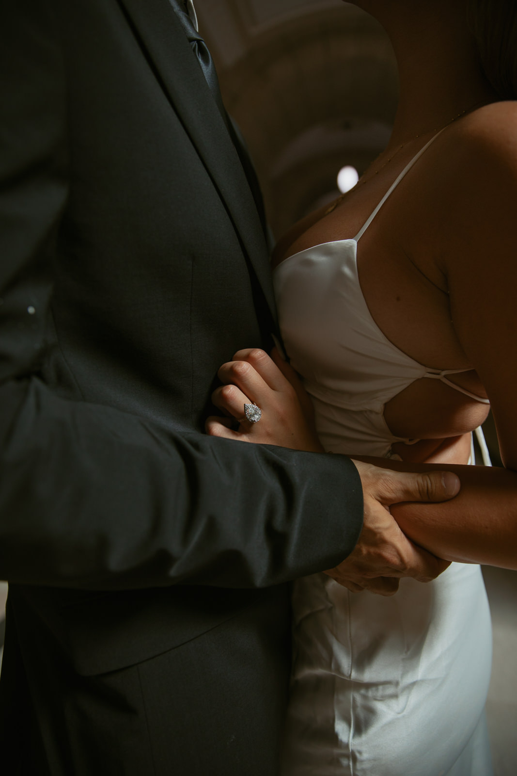couple embracing. showcases large diamond ring.