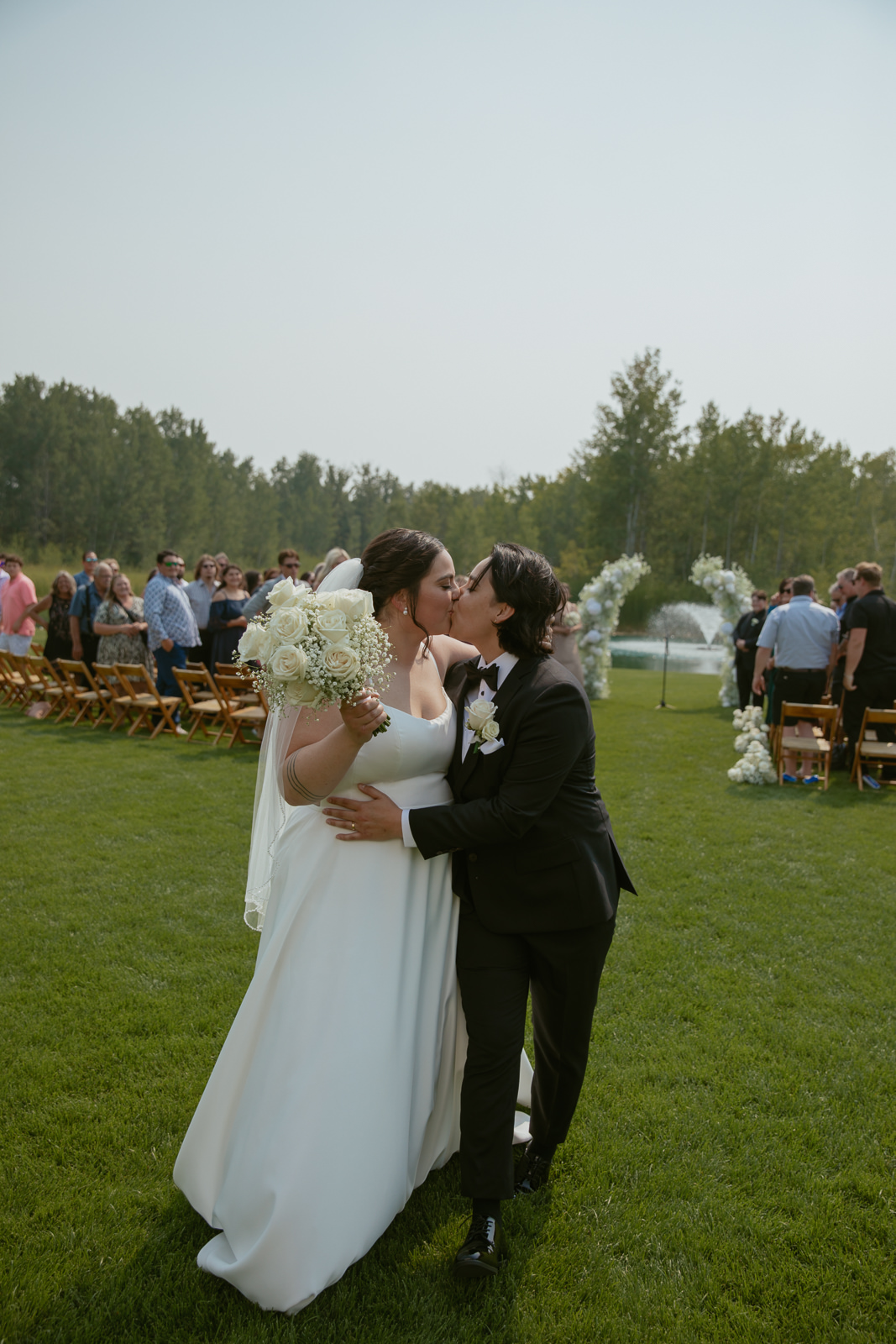 Bride & Bride kissing at the end of ceremony aisle