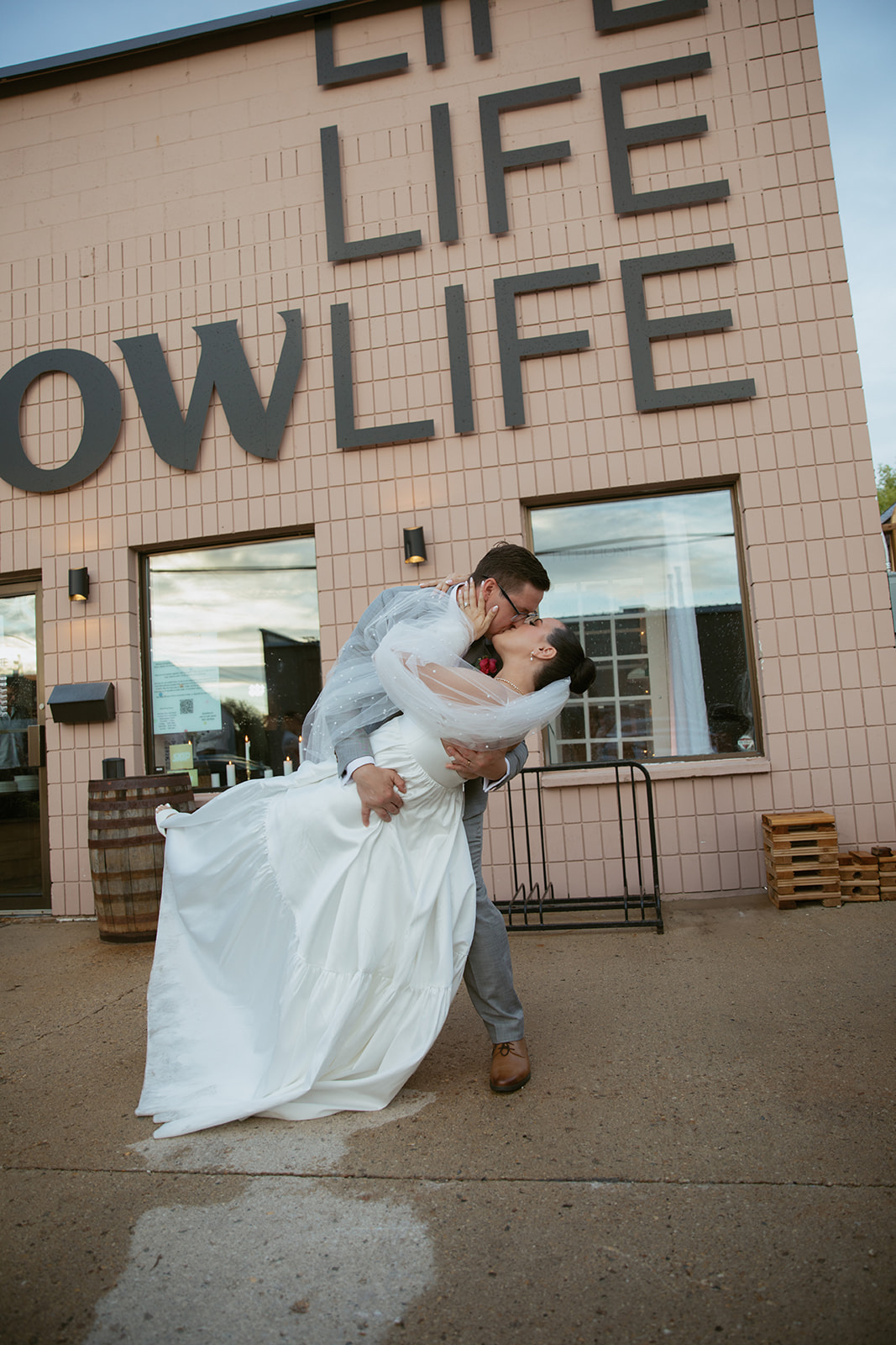 Groom dipping & kissing bride in front of brewery wedding venue
