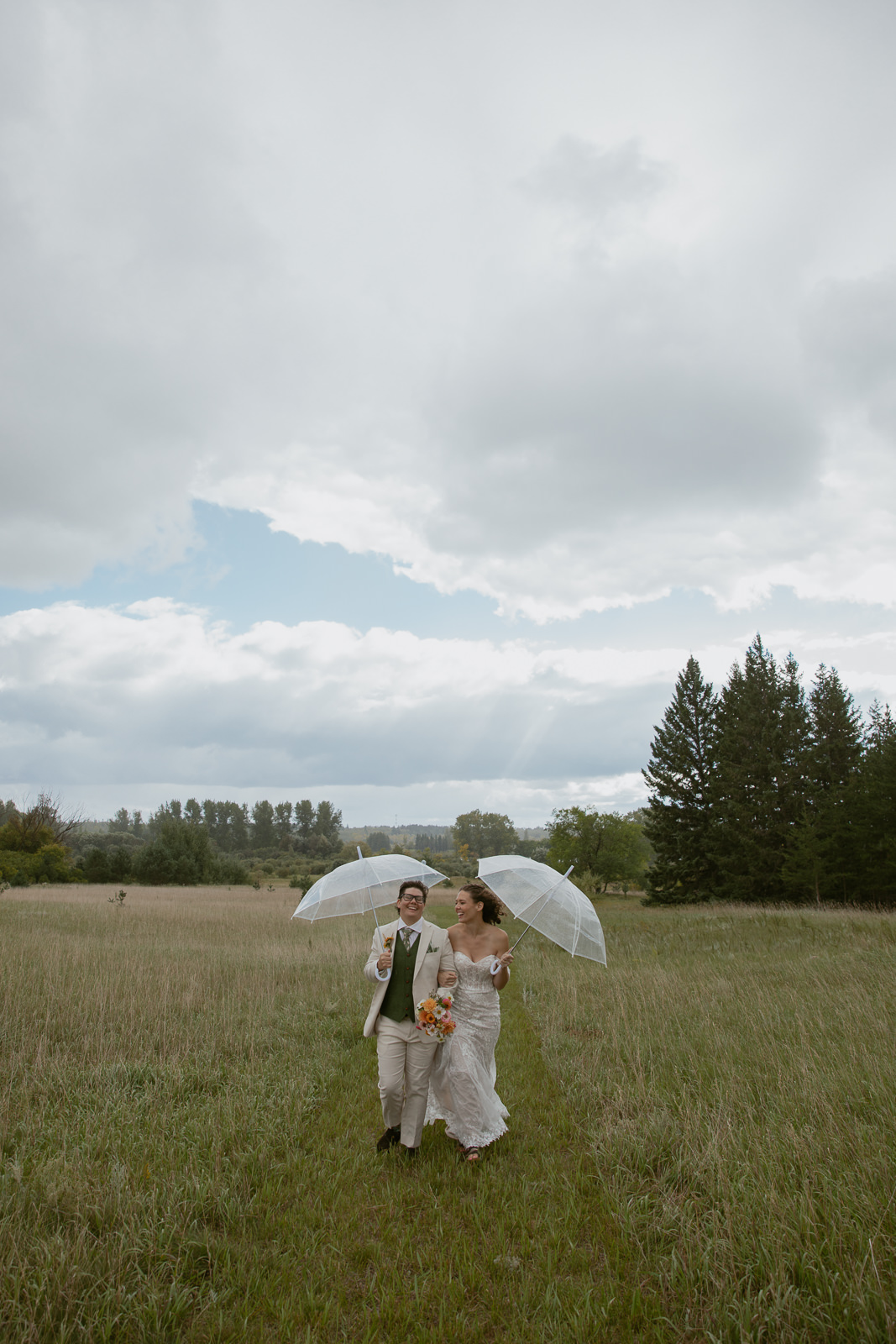 Bride & Bride walking in the rain with umbrellas