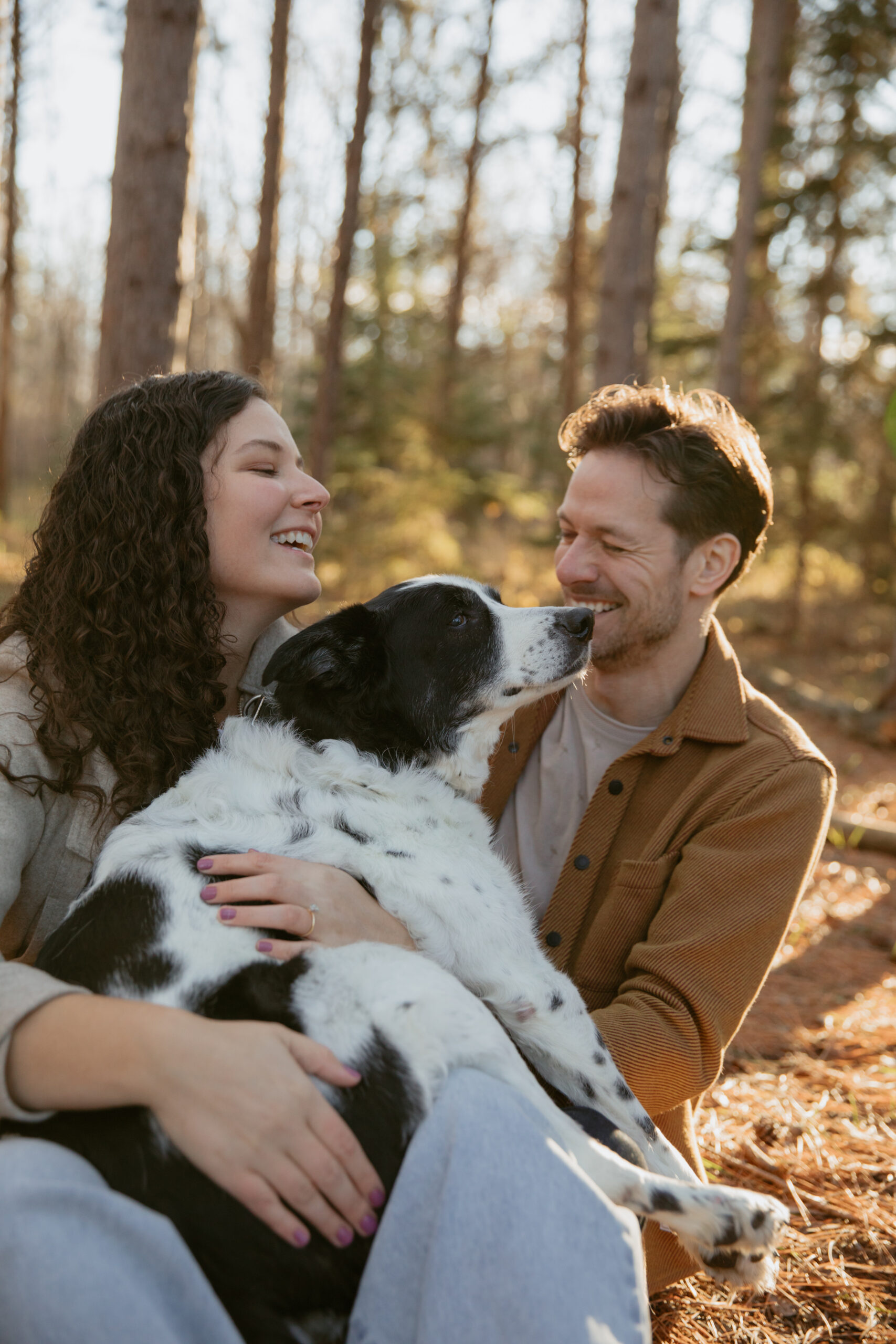Couple sitting on ground kissing their dog