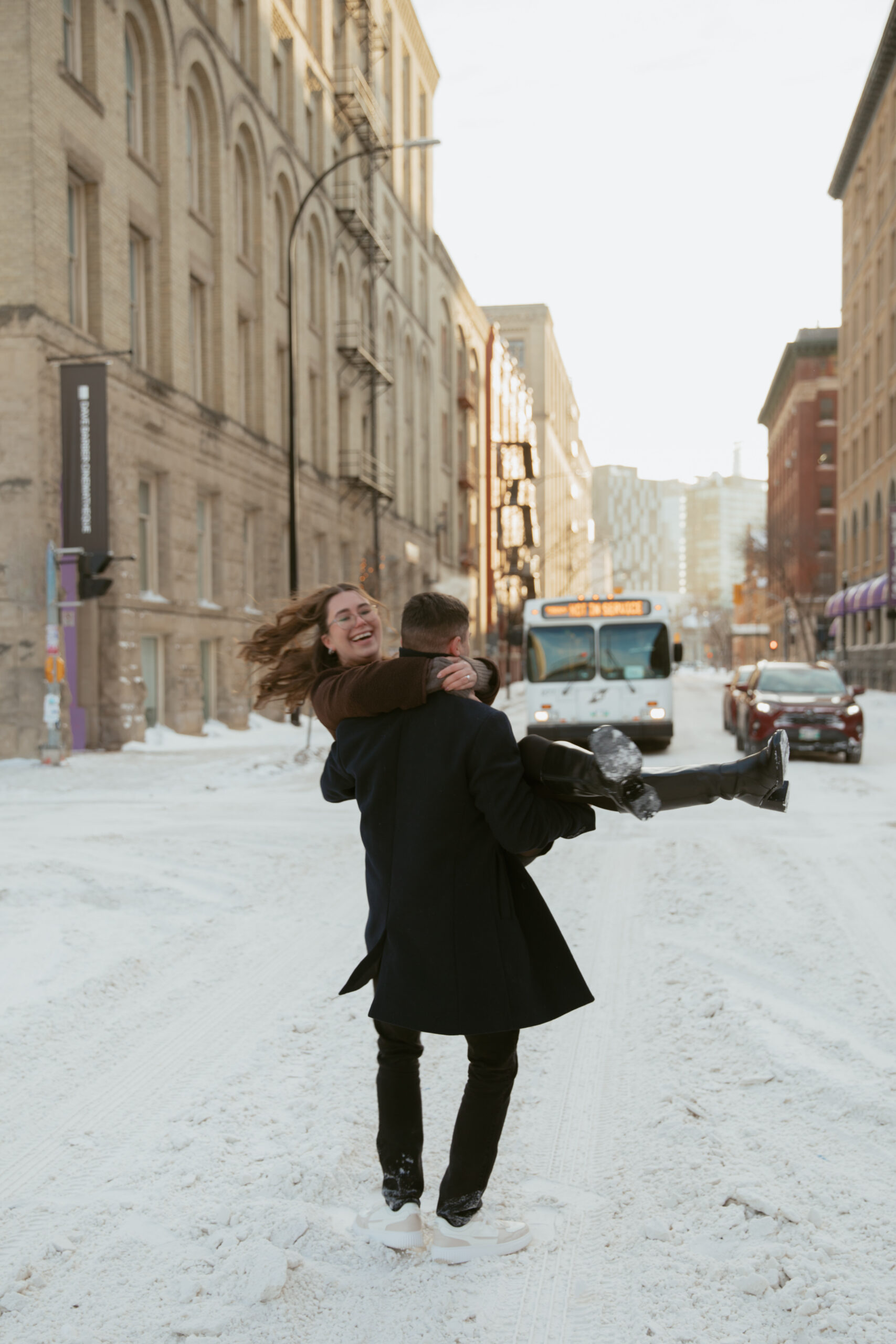 man spinning woman in the middle of a downtown winter street