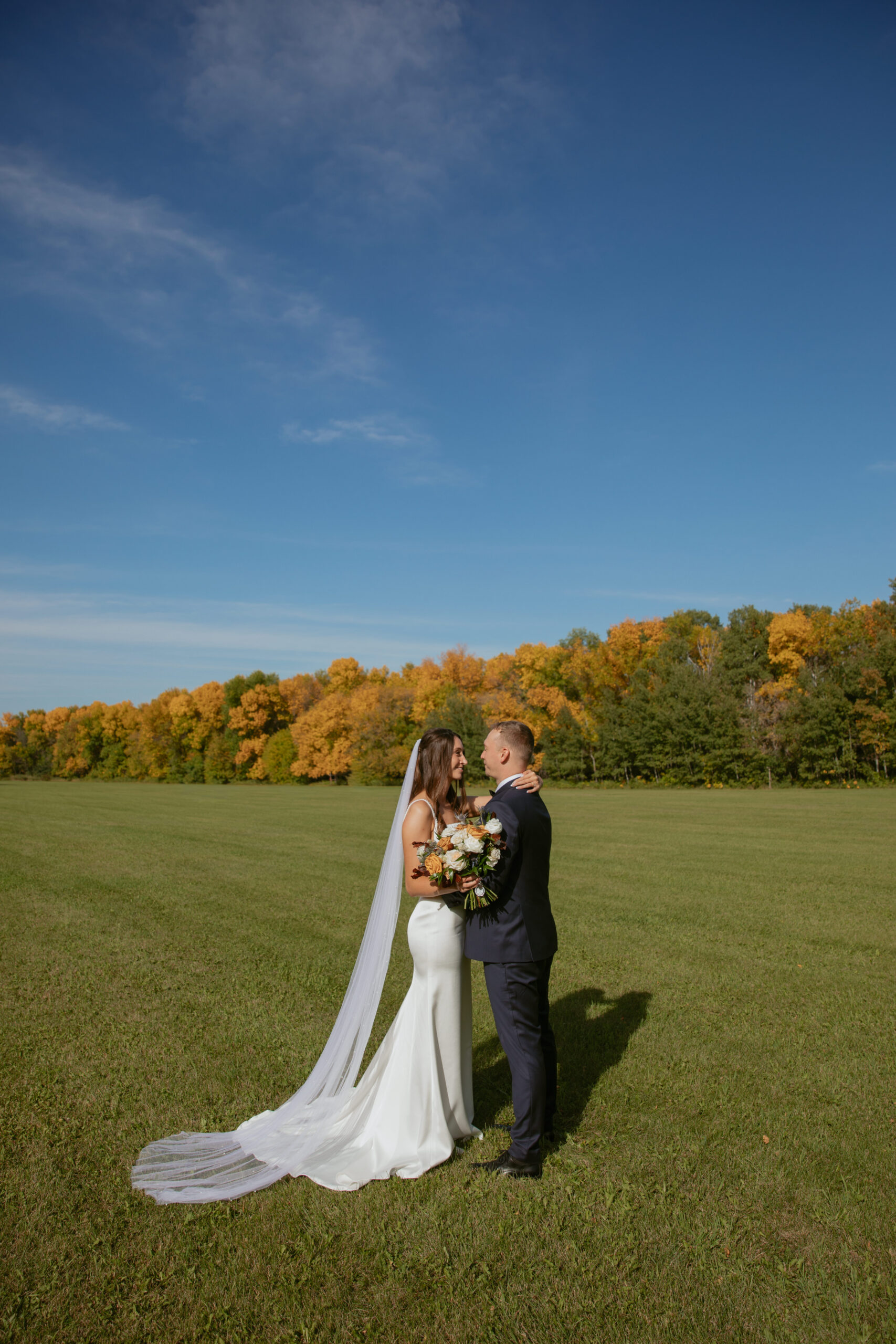 bride & groom in a field with autumn foliage